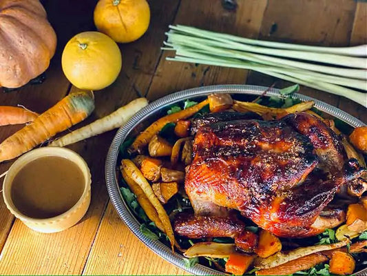 A golden-brown roasted whole chicken with herbs in a pot, surrounded by savory juices.