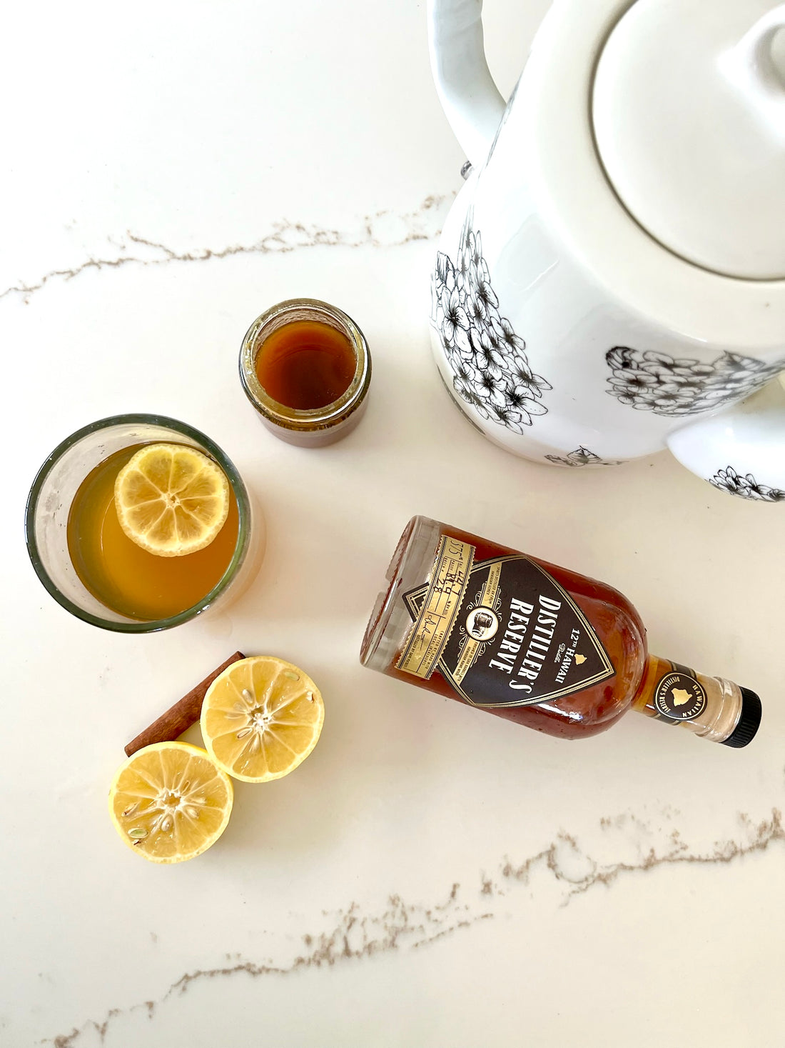 A warm Hot Toddy with local whiskey, honey, and lemon, garnished with a lemon slice and cinnamon stick in a cozy cup.