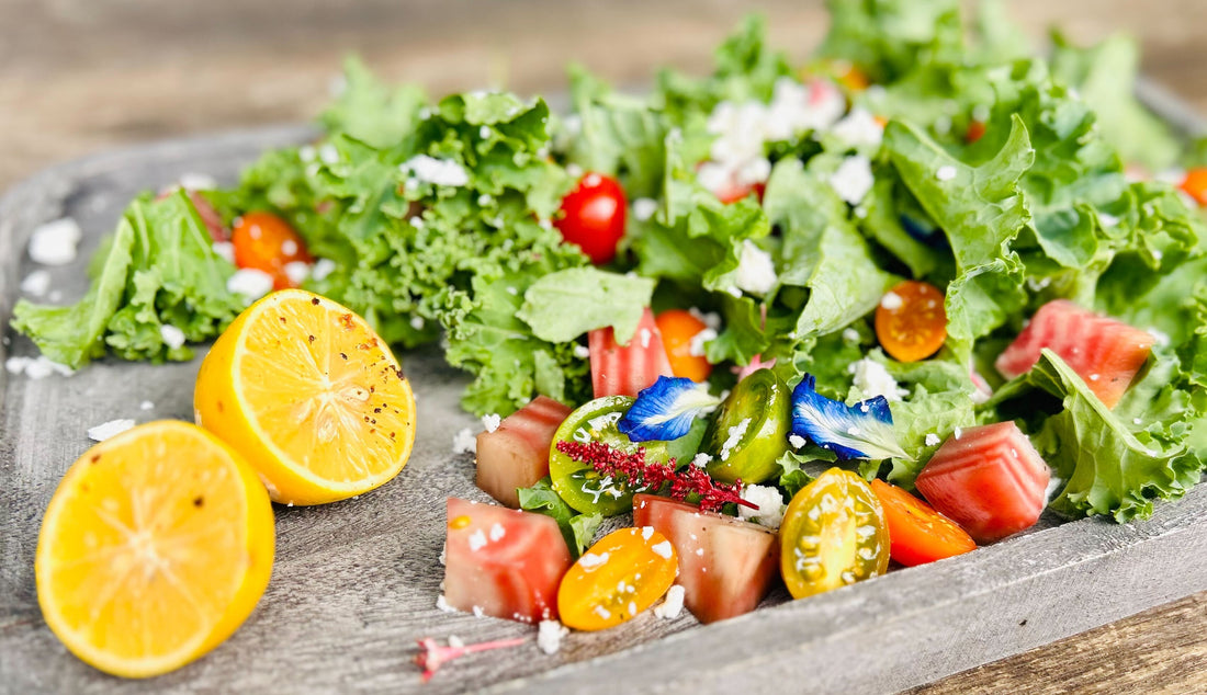  A fresh salad with greens, cherry tomatoes, beets, edible flowers, feta, and charred lemons on a rustic platter.