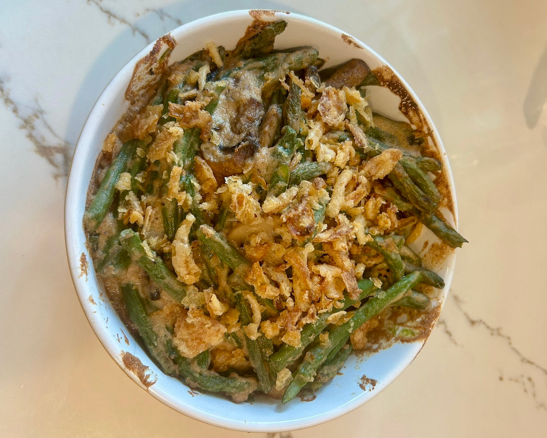 Green bean and mushroom casserole topped with crispy onions, made with locally sourced ingredients including organic green beans, Keiki crimini mushrooms, and macadamia nut “parm,” baked to a golden, bubbling finish.